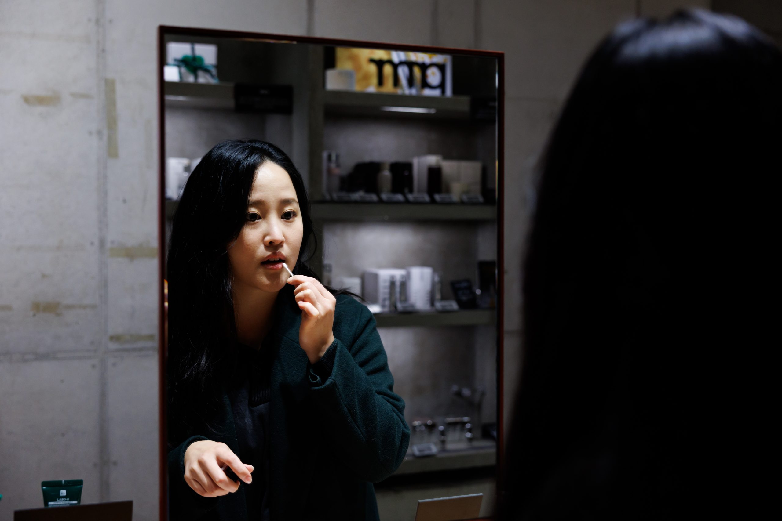 거울 앞에서 립스틱을 바르고 있는 여성의 모습