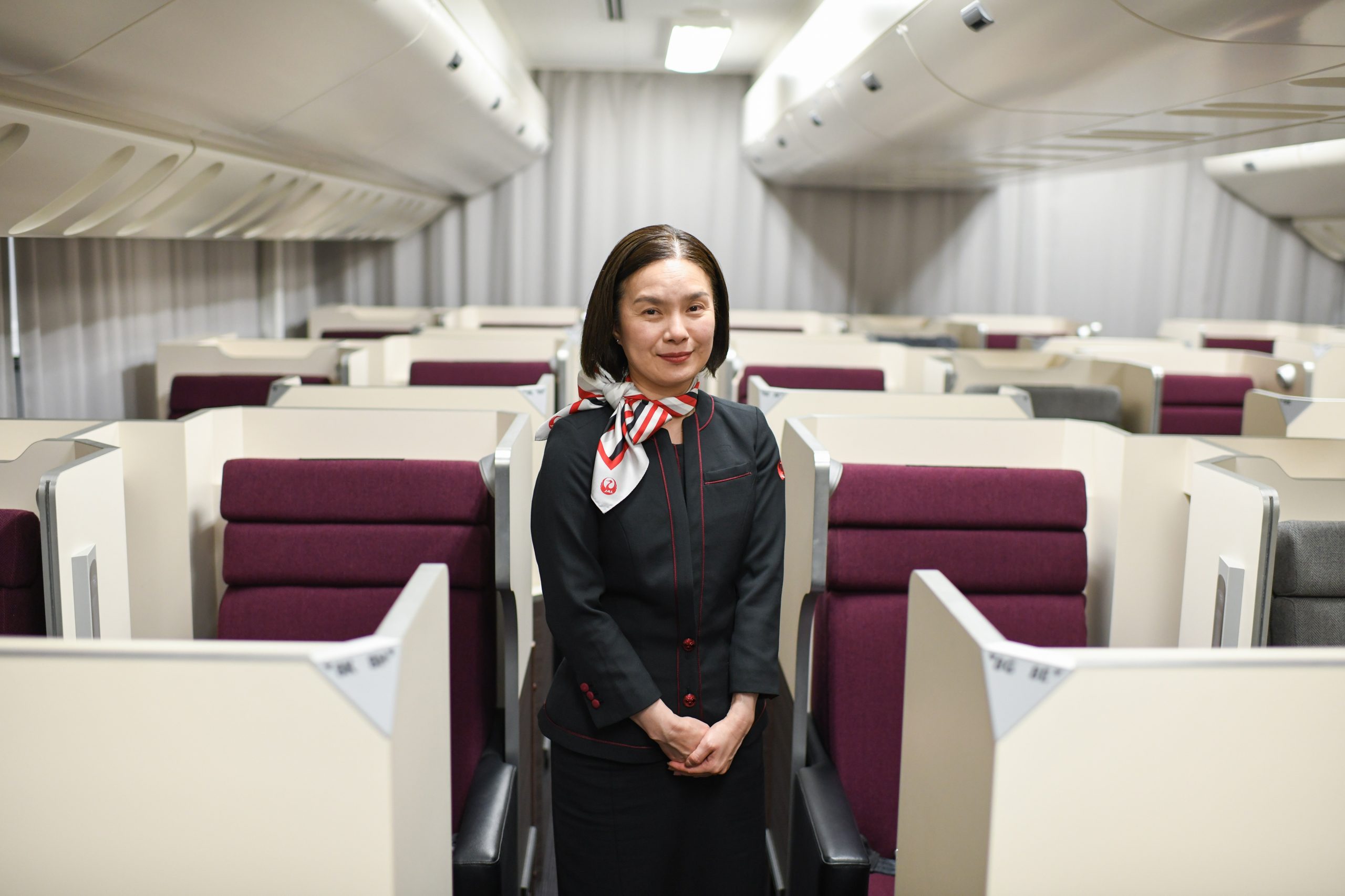 客室乗務員の制服を着た女性が機内の通路に立っている