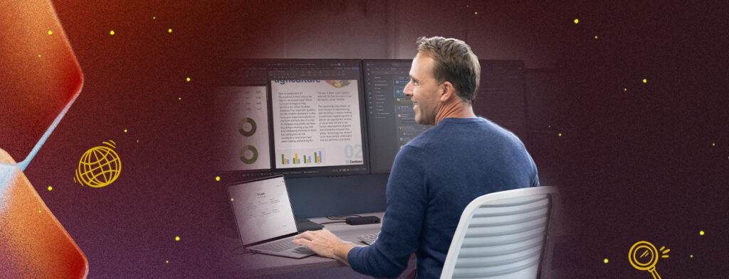 A man sits at a desk with a laptop and two monitors; colorful background with shapes