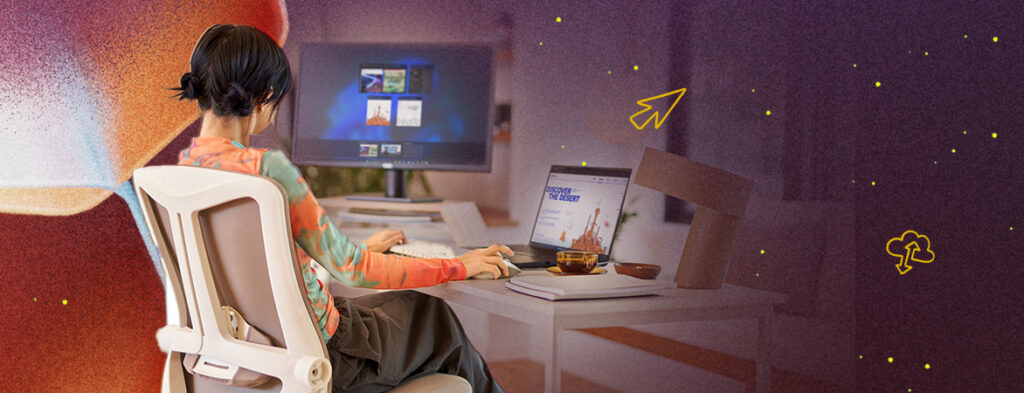 A person sits at a home desk with a laptop and a monitor; colorful background with shapes