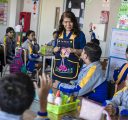 A female teacher stands amidst students in a classroom