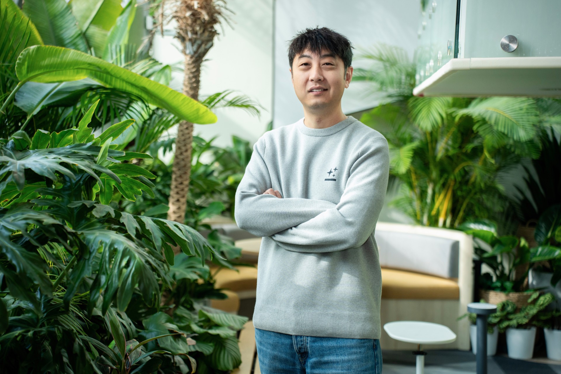 A man standing in an indoor garden with plants in the background.