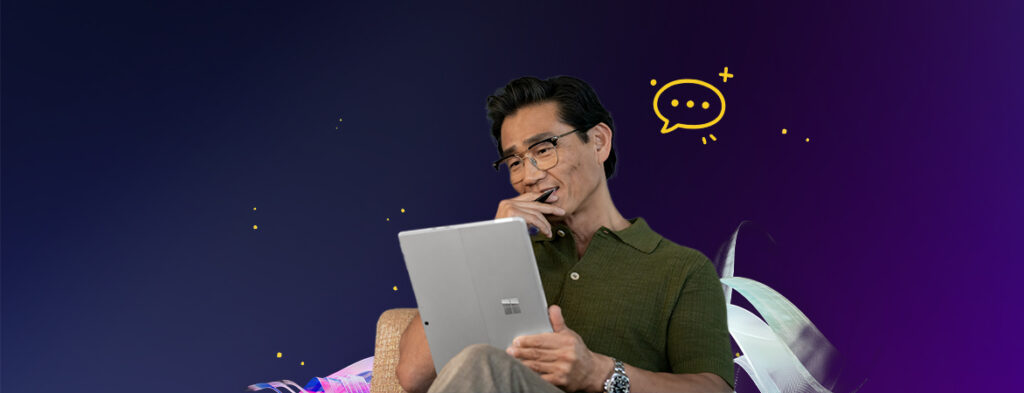 A man sits on a chair with a tablet computer in one hand and a stylus in another, on a background of colorful shapes.