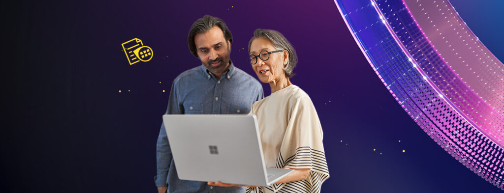 A man and woman standing looking at a laptop that the woman is holding, on a background of colorful shapes.