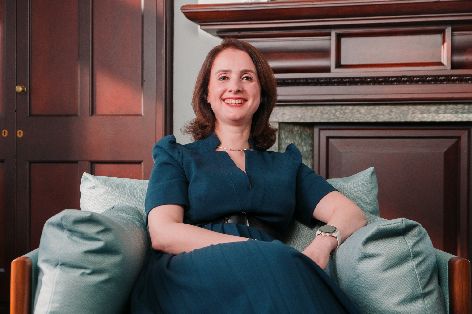 Portrait of a smiling brunette woman seated in an armchair.