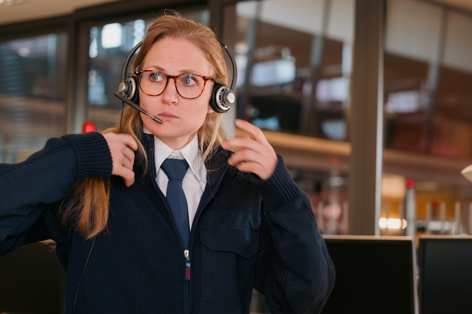 Frau mit langen blonden Haaren in einer blauen Uniform, die ein Telefon-Headset trägt.
