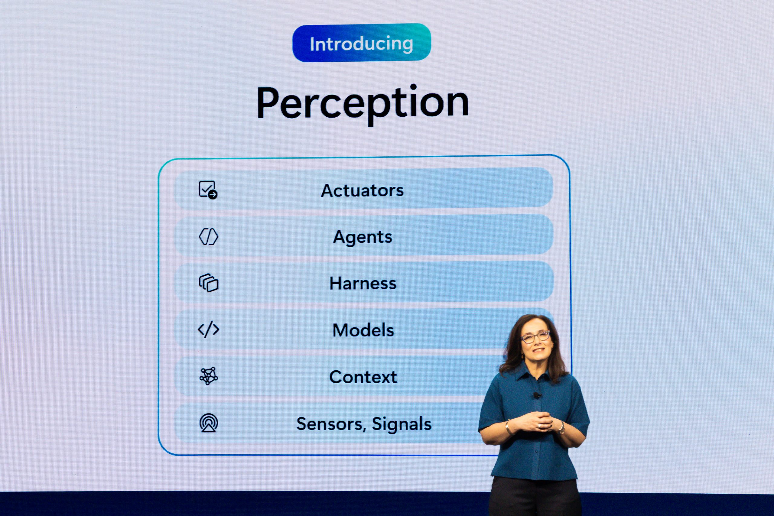 A woman speaks onstage during a presentation.
