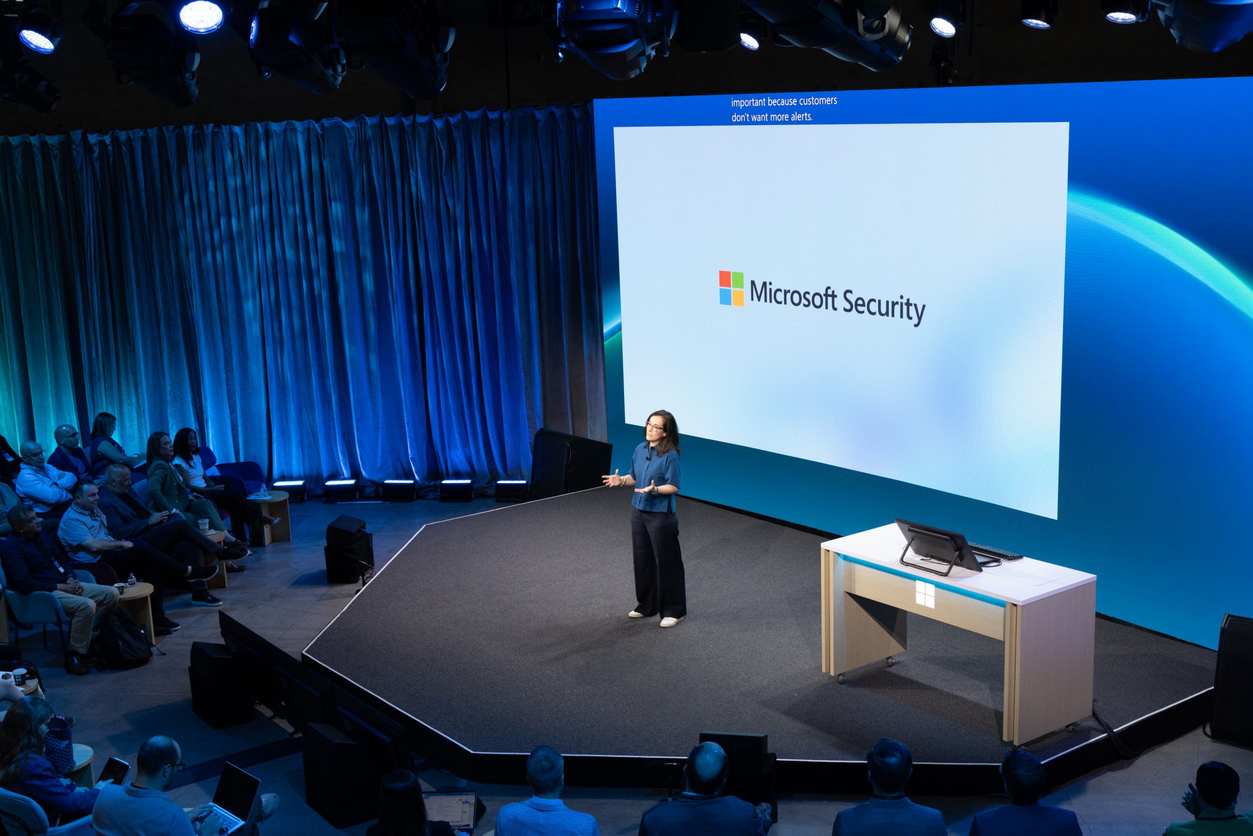 A woman speaks onstage during a presentation.