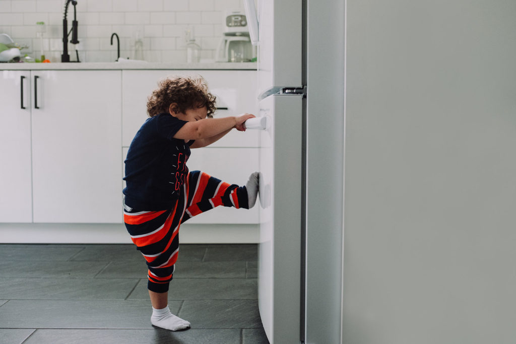 child opening a fridge door