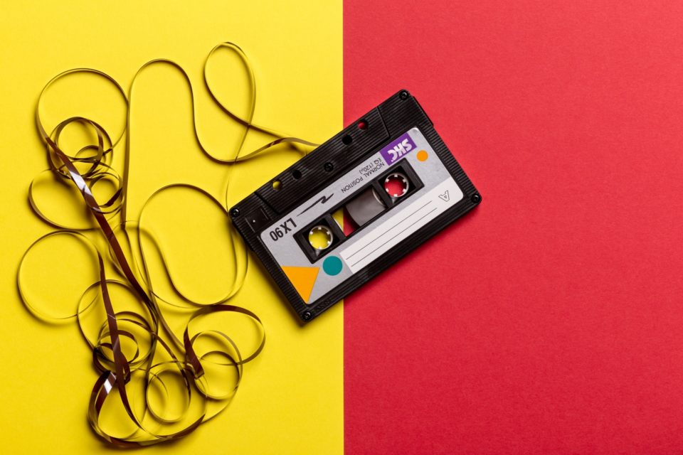 partially unravelled cassette tape on a yellow and red background