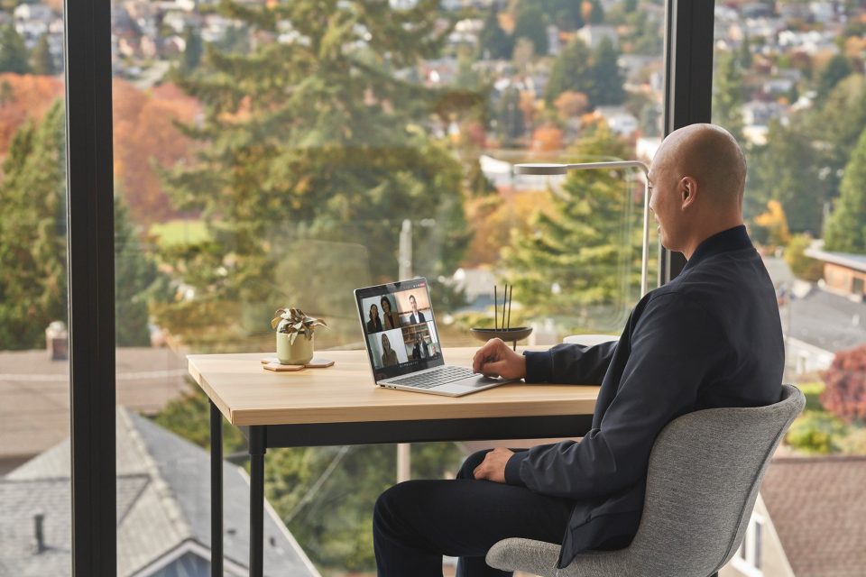 A man sitting at a desk at home with a Surface Laptop Go 2 on a Teams call