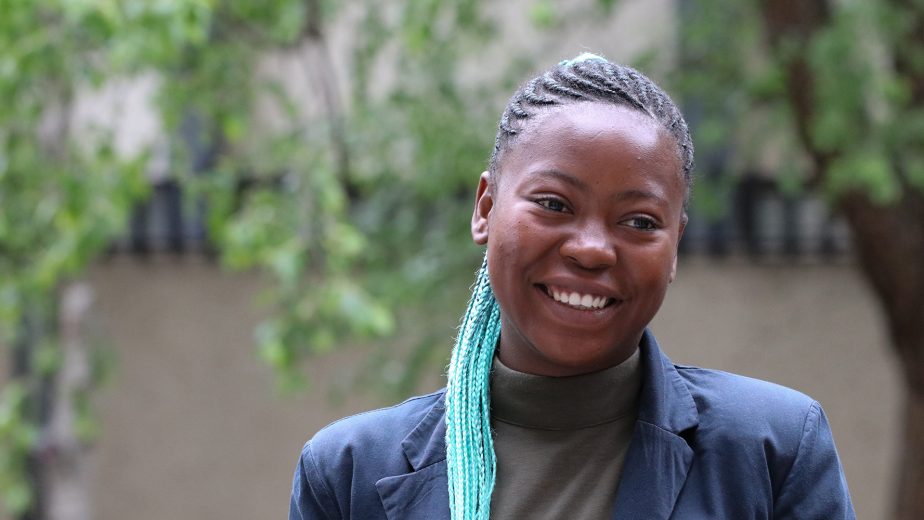 Woman outside with trees behind her